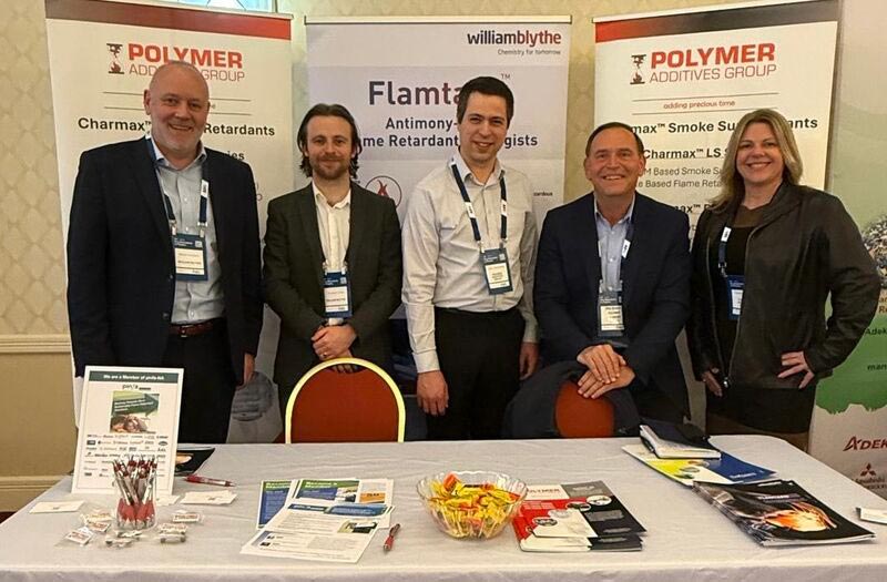 Pag-expo-table | Polymer Additives Group Pag Employees Stand Together by Their Table at a Convention.